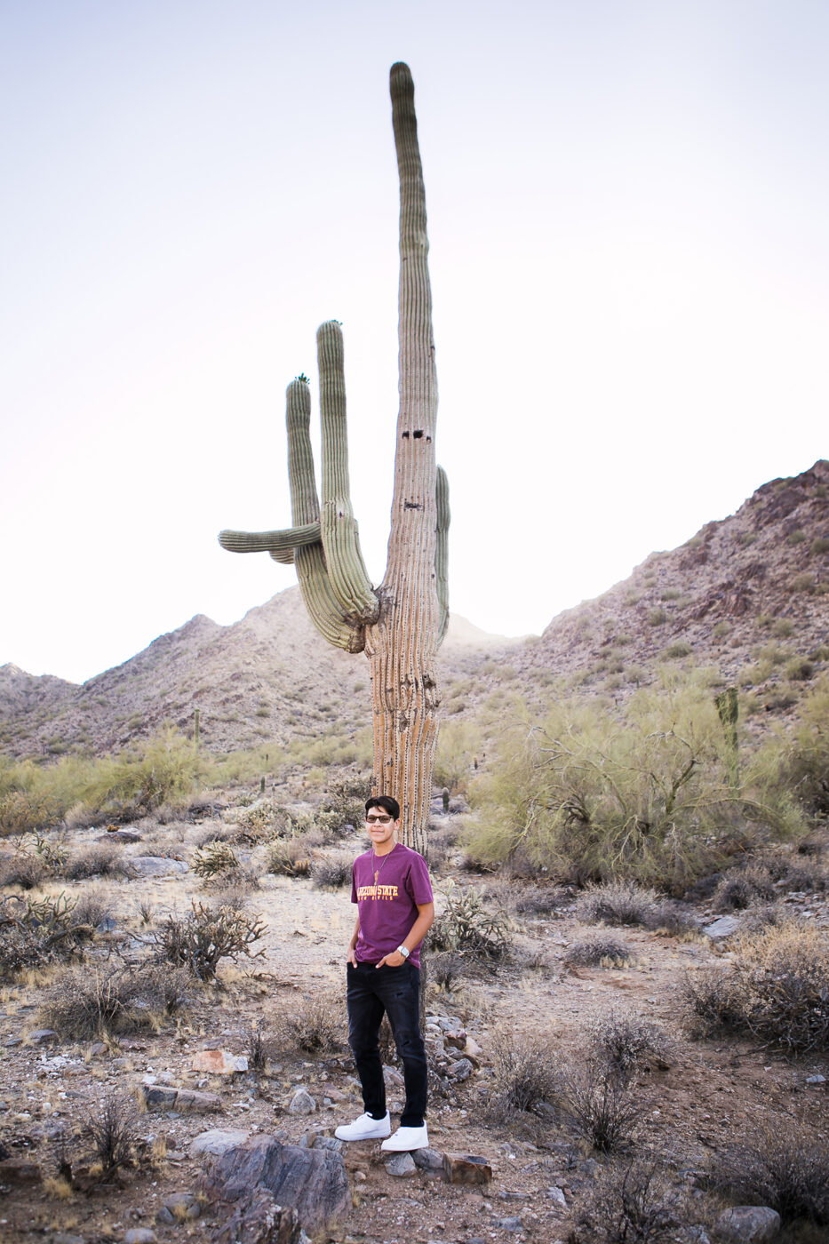 Large saguaro cactus behind high school senior wearing an ASU shirt. 