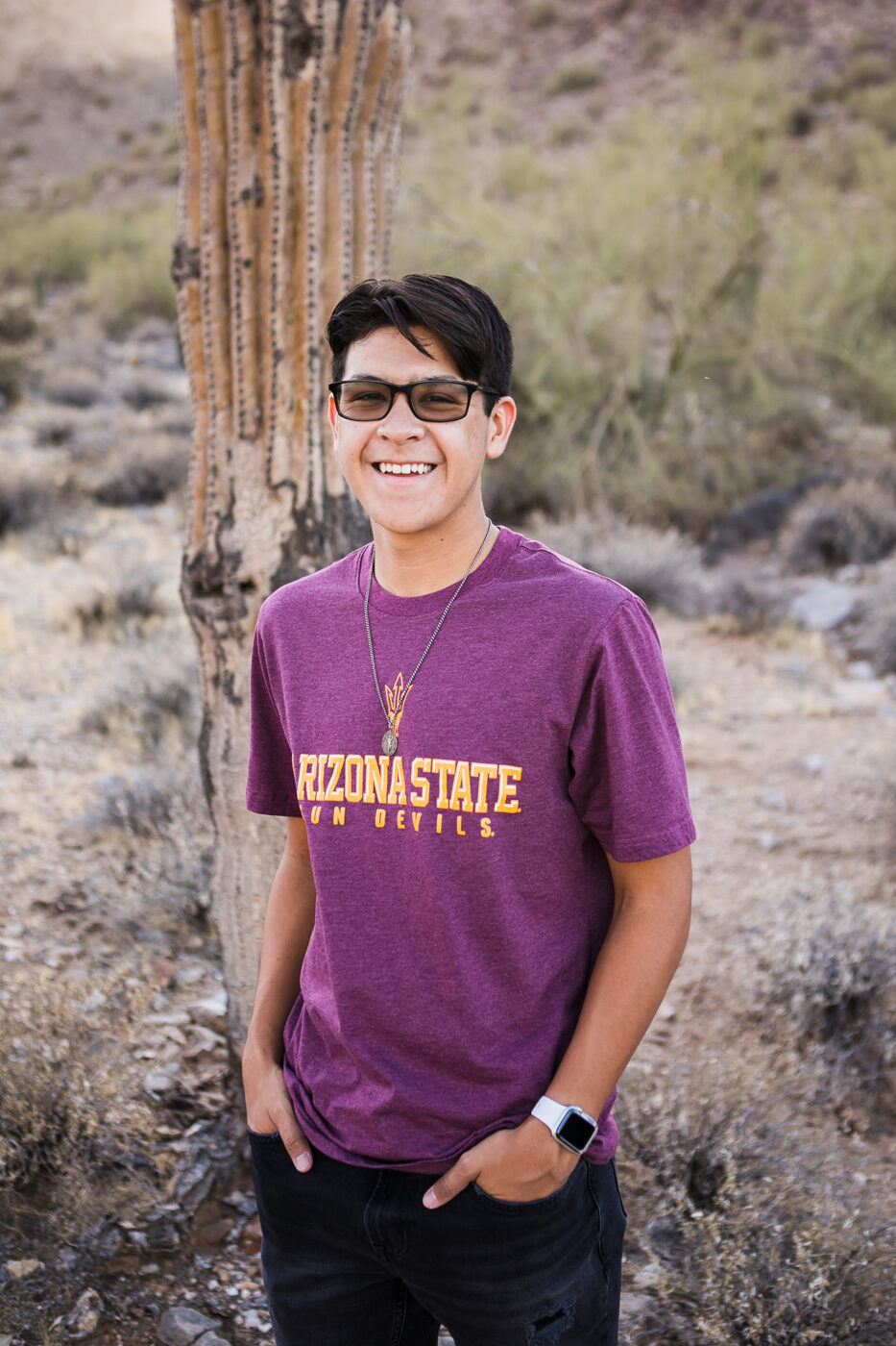 Smiling high school senior with a cactus behind him.
