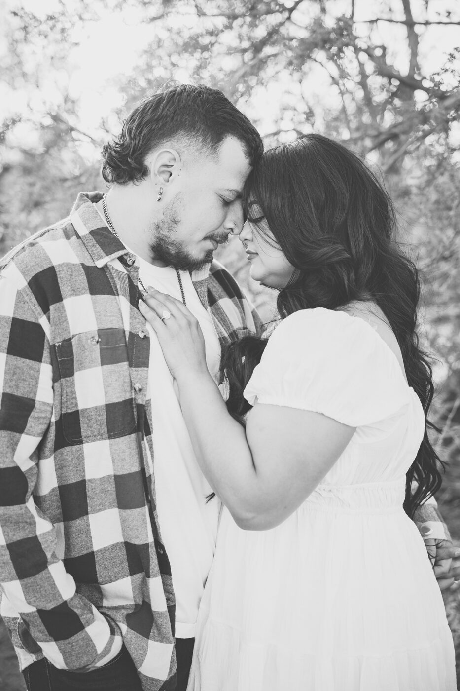 Couple with their foreheads together looking down, in black and white.