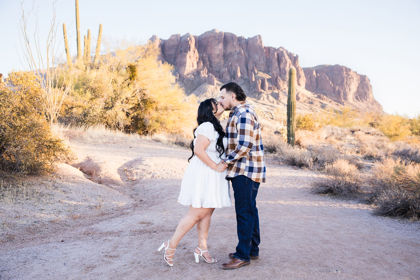 Couple kissing in front of the Superstition Mountains at sunset.