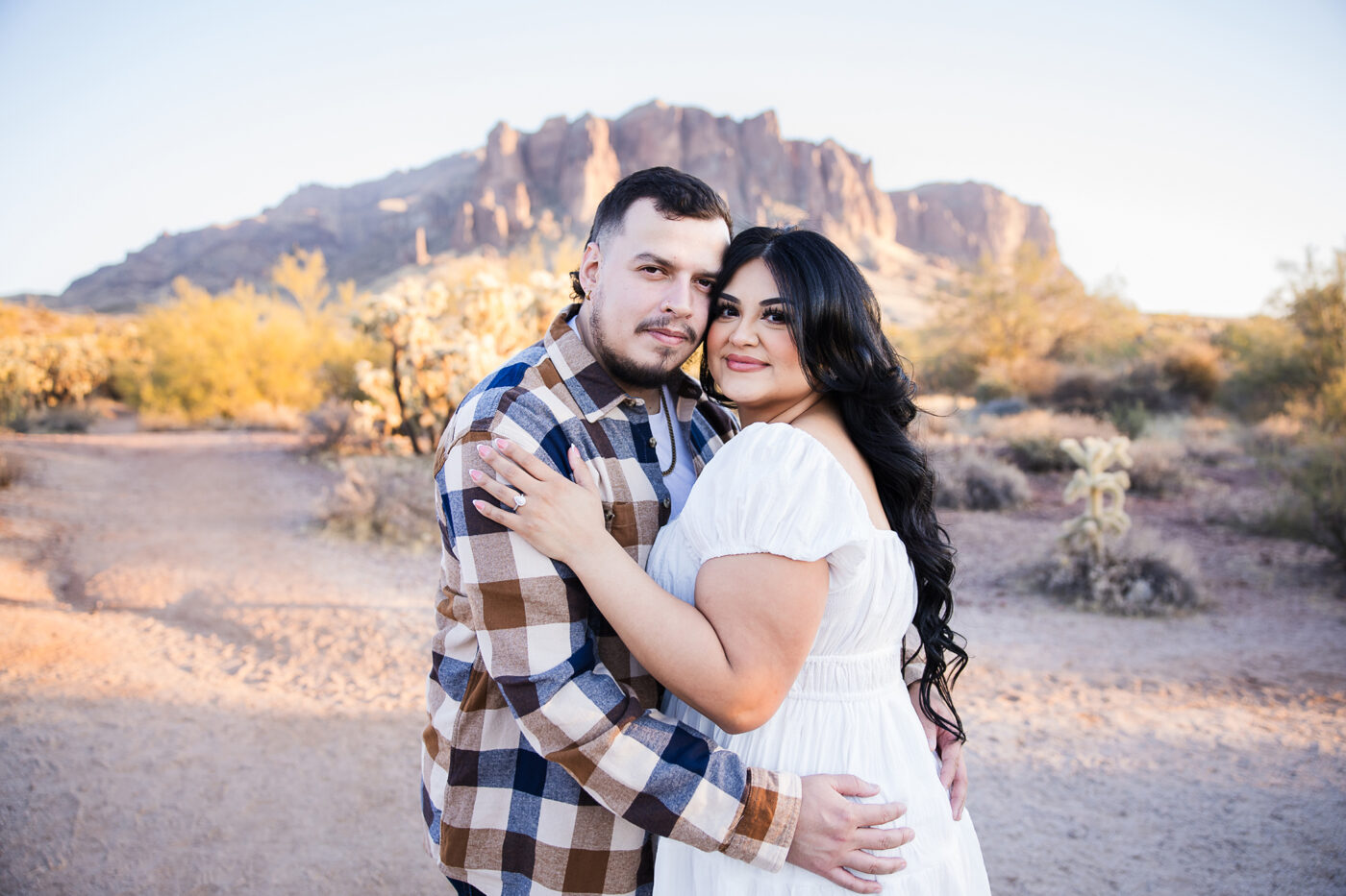 Close up of engaged couple hugging each other with Superstition Mountain in the background.
