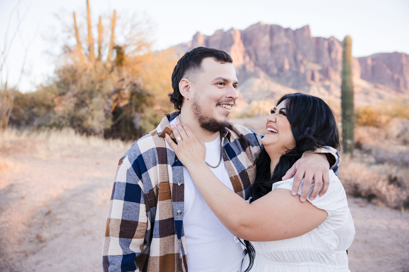 Close up of engaged couple laughing together with Superstition Mountain in the background.