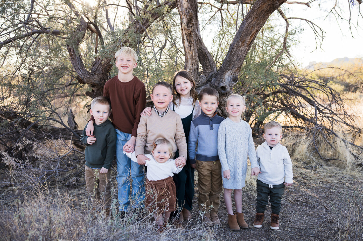 A group of small grandkids with trees behind smiling at camera.