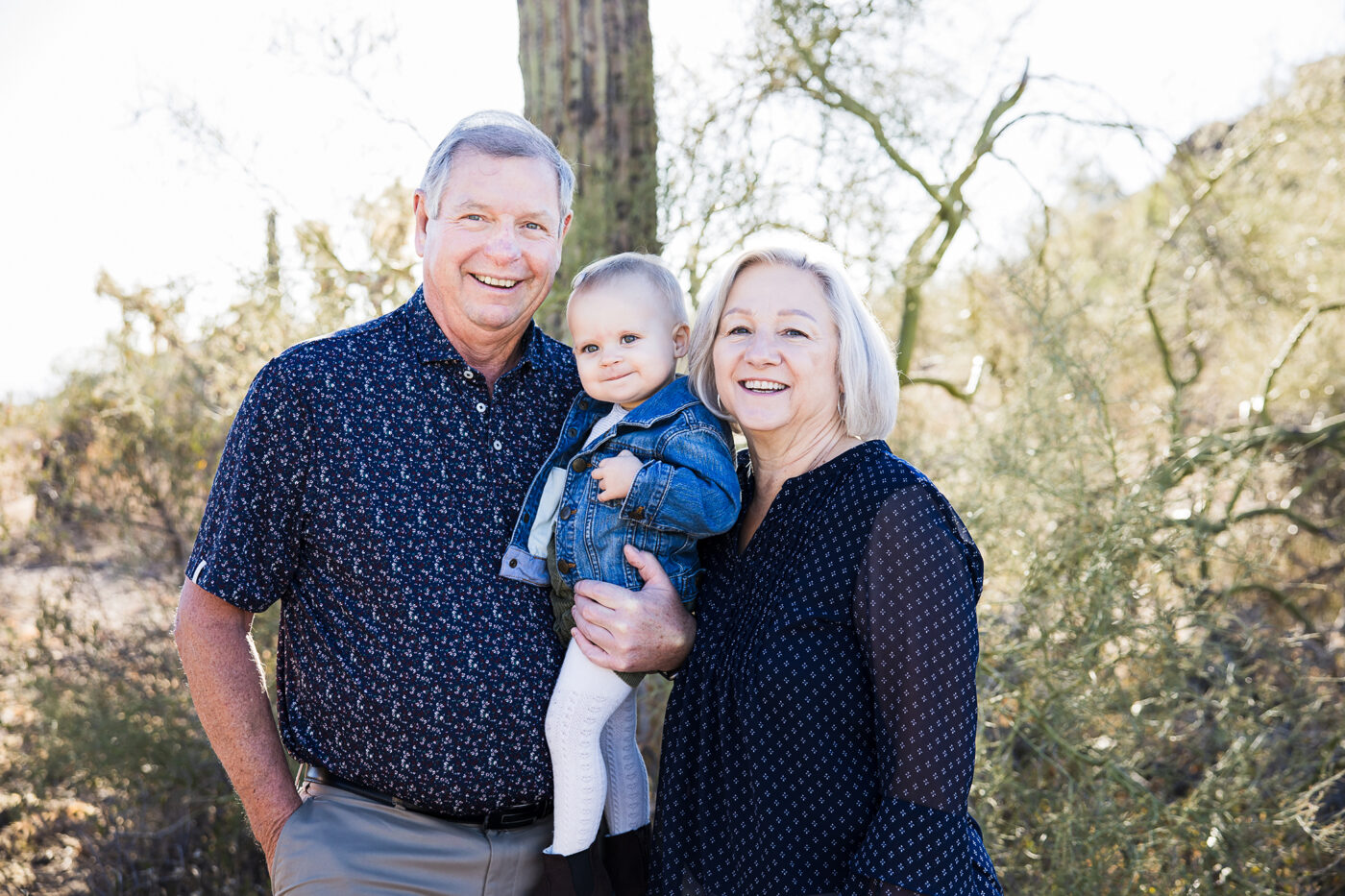 Grandparents holding small grandbaby girl in the desert. 