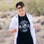 High school senior boy holding open his baseball jersey to see senior shirt underneath.