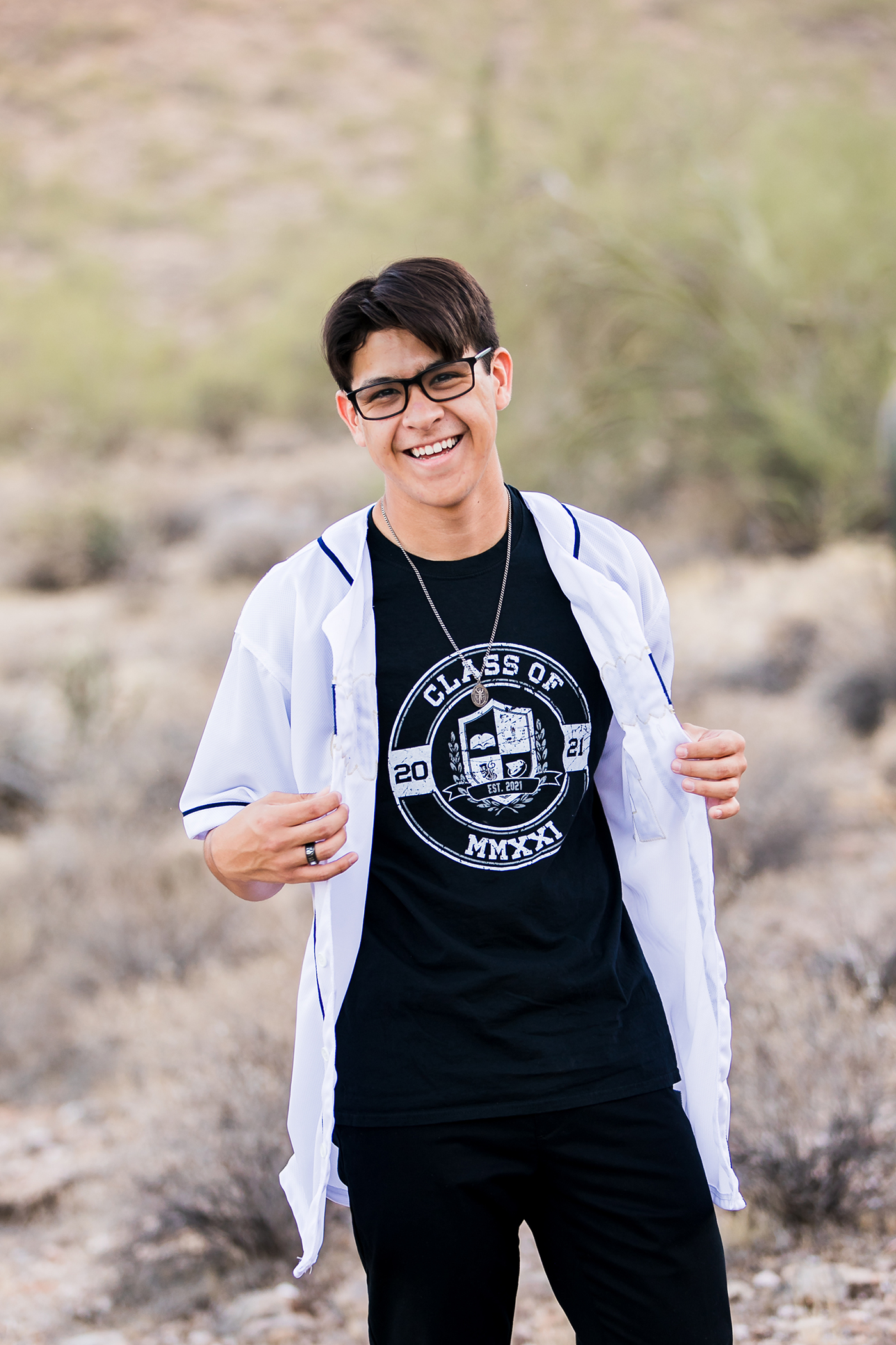 High school senior boy holding open his baseball jersey to see senior shirt underneath.
