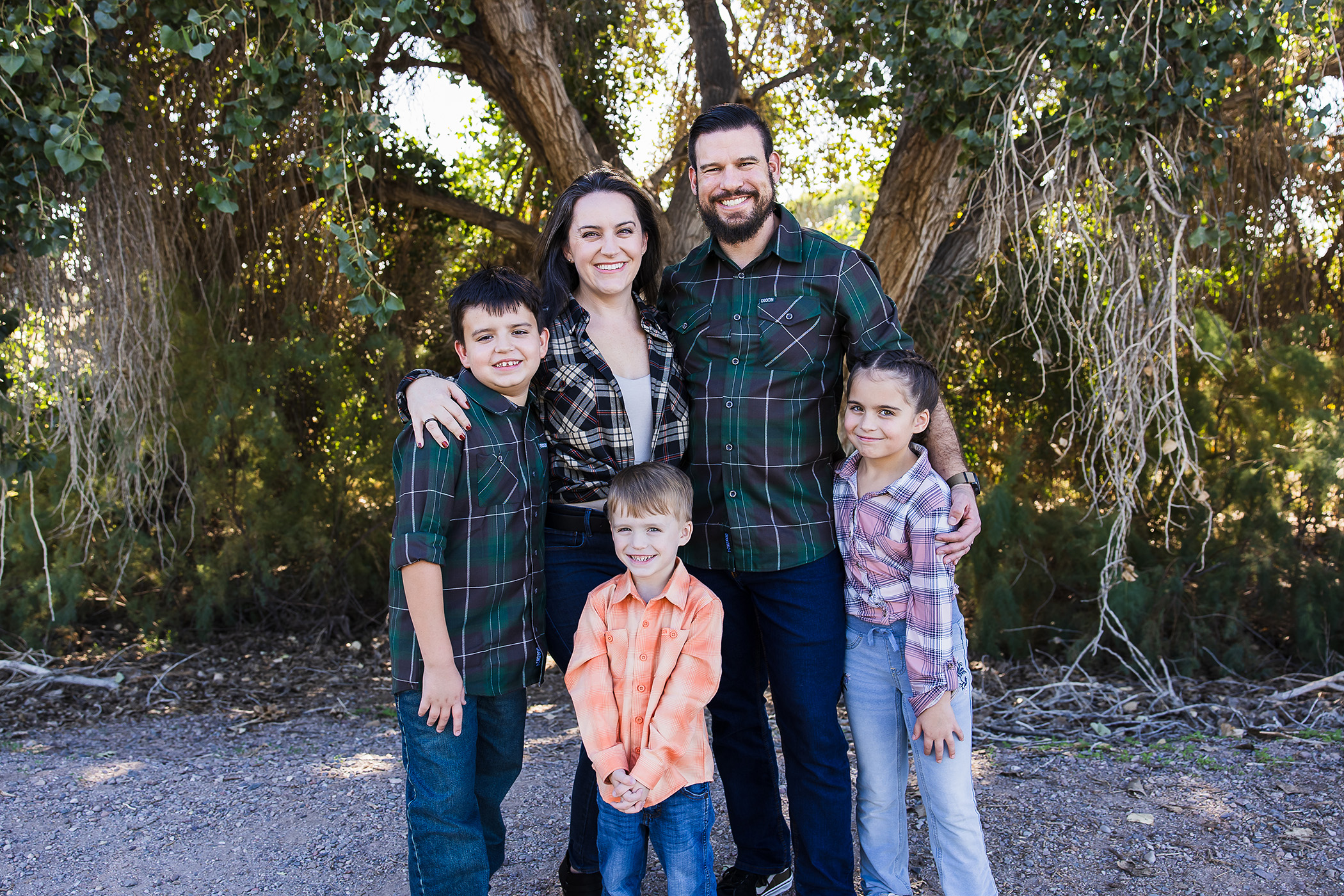 Family in plaid posing in front of cool trees.