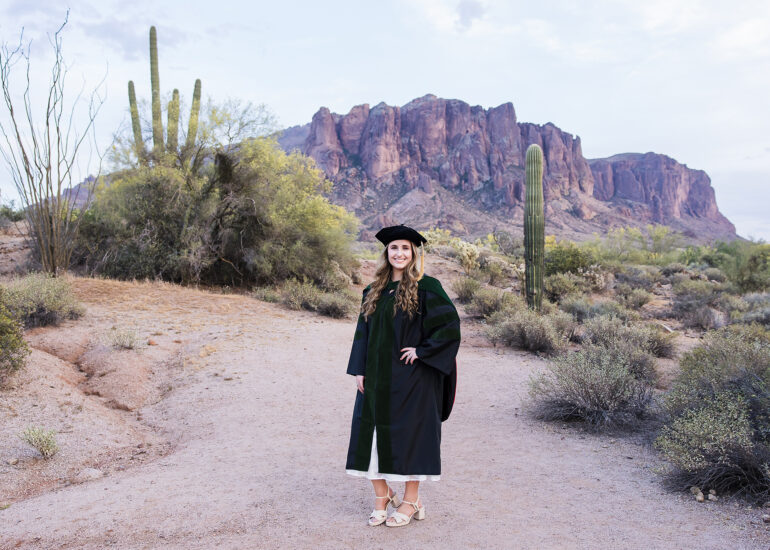 graduate in medical cap and gown in front of superstition mountain
